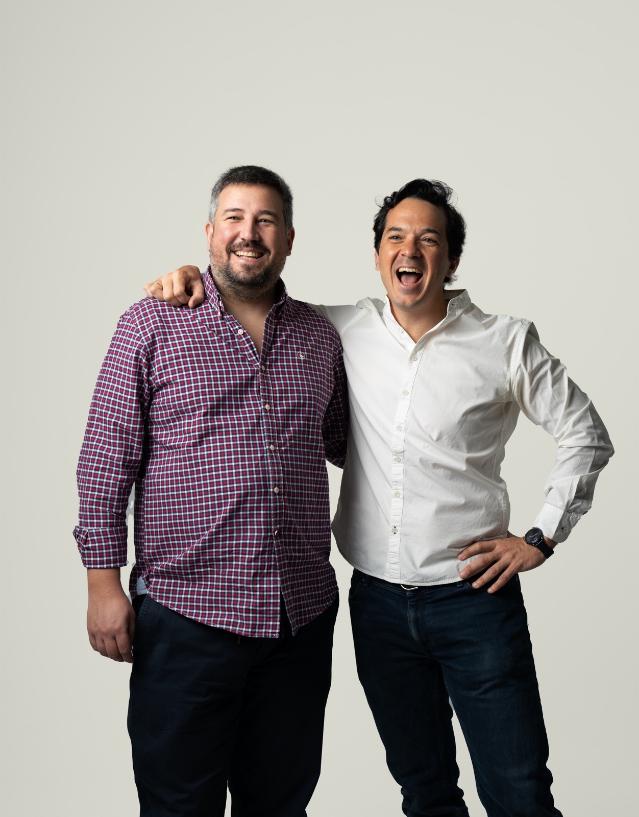 Two men posing together against a plain background