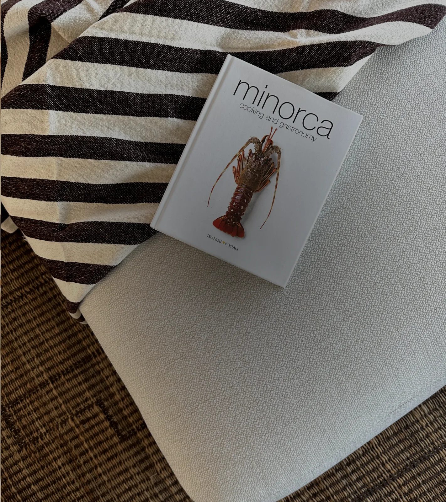 A Menorcan cookbook resting on a striped cushion